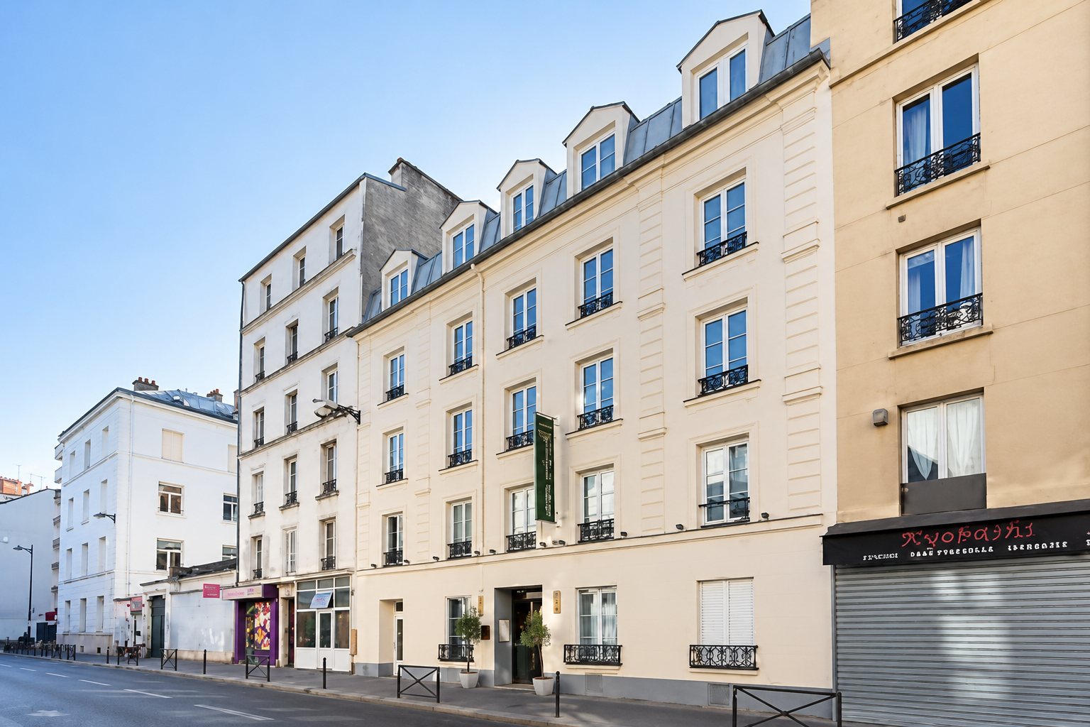 Vue d'une rue avec un long immeuble de pierre claire aux balcons en fer forgé, sous un ciel bleu.